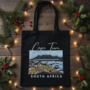 Black Graphic Tote Bag with a view of Table Mountain from Blaauwberg Beach with sand dunes and flora as well as the vastness of the Atlantic Ocean in Cape Town, South Africa - Tabletop Serenity by René Tesner - Product (Informative)